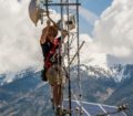 A man installs monitoring equipment atop an antennae tower