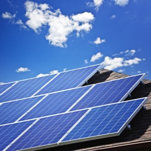 Solar panels mounted on a residential rooftop, against a sunny sky.